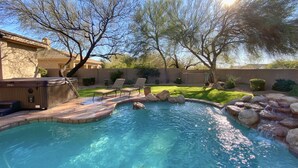 Un jardin avec une piscine, des chaises longues et un jacuzzi.