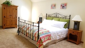 Quarto com estrutura de cama de metal, guarda-roupa de madeira, duas mesas de cabeceira com abajures e cabeceira verde.