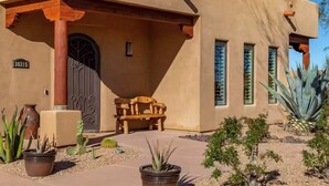 A stucco building with a wooden bench, a gate, and potted plants. - Serene Scottsdale Home:Heated Pool,HotTub,FirePit,Putting Green & Mountain Views (Scottsdale)