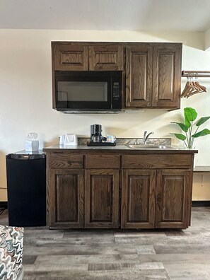 A kitchen with wooden cabinets, a built-in microwave, a coffee maker, and a sink.