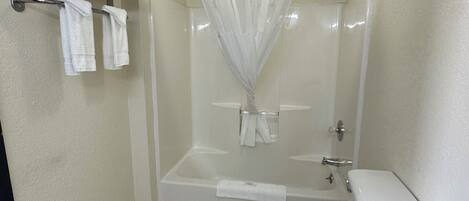 A bathroom with a toilet, a bathtub with a shower curtain, and a towel rack with folded towels.