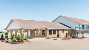 A building with a covered entrance, a brick facade, and a flat roof.