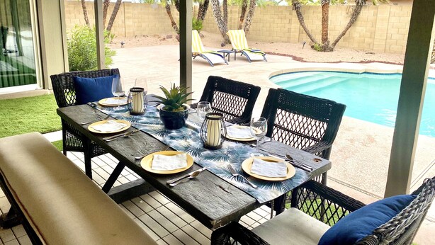 Eine überdachte Terrasse mit Pool, Gartenmöbeln und einem für das Essen gedeckten Tisch.