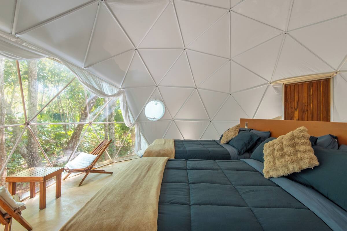 Een koepelvormige kamer met een bed, een tafel en een stoel.