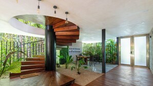 A modern interior with a wooden staircase, a dining area, and a view of greenery outside.