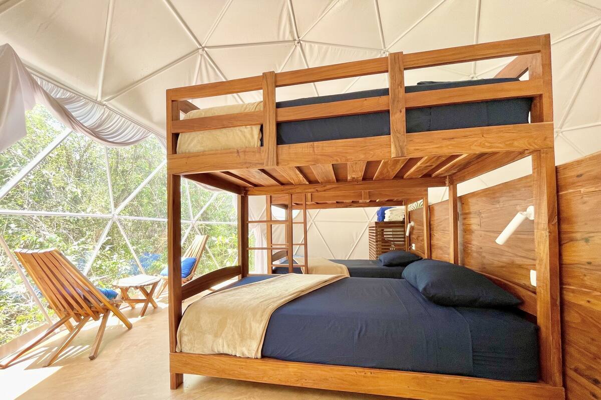 Een houten stapelbed met uitzicht op groen buiten.