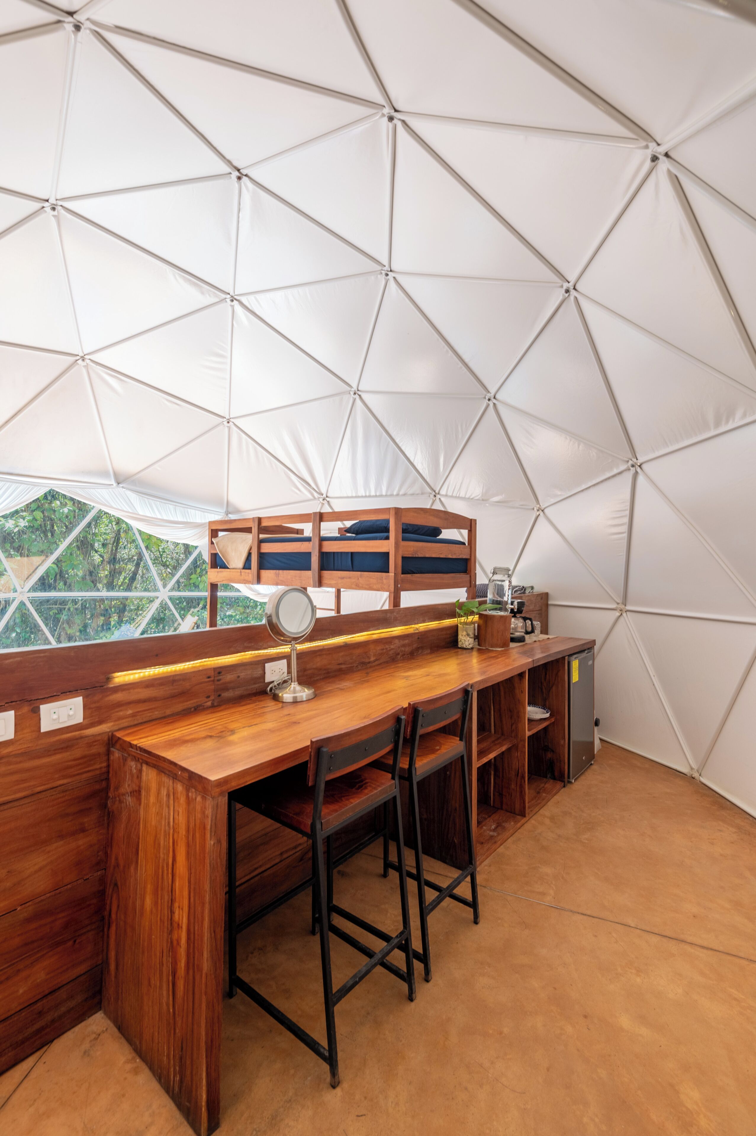A tent with a wooden desk, chairs, and bunk beds.