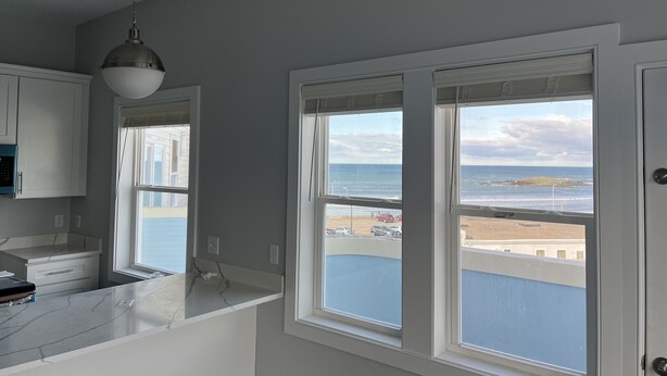 A kitchen with a view of the beach, a pendant light, and a white door. - Direct Ocean Front Condo with large wrap around balcony (Hull)