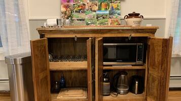 Un meuble de cuisine en bois, doté d’étagères ouvertes, d’un four à micro-ondes et d’une machine à café.