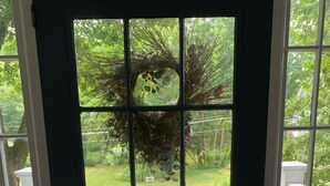 A view through a door with a wreath, a paved pathway, and a white fence. - Walk into town, soak up sun on enclosed porch & steps away from nature trails! (Stockbridge)