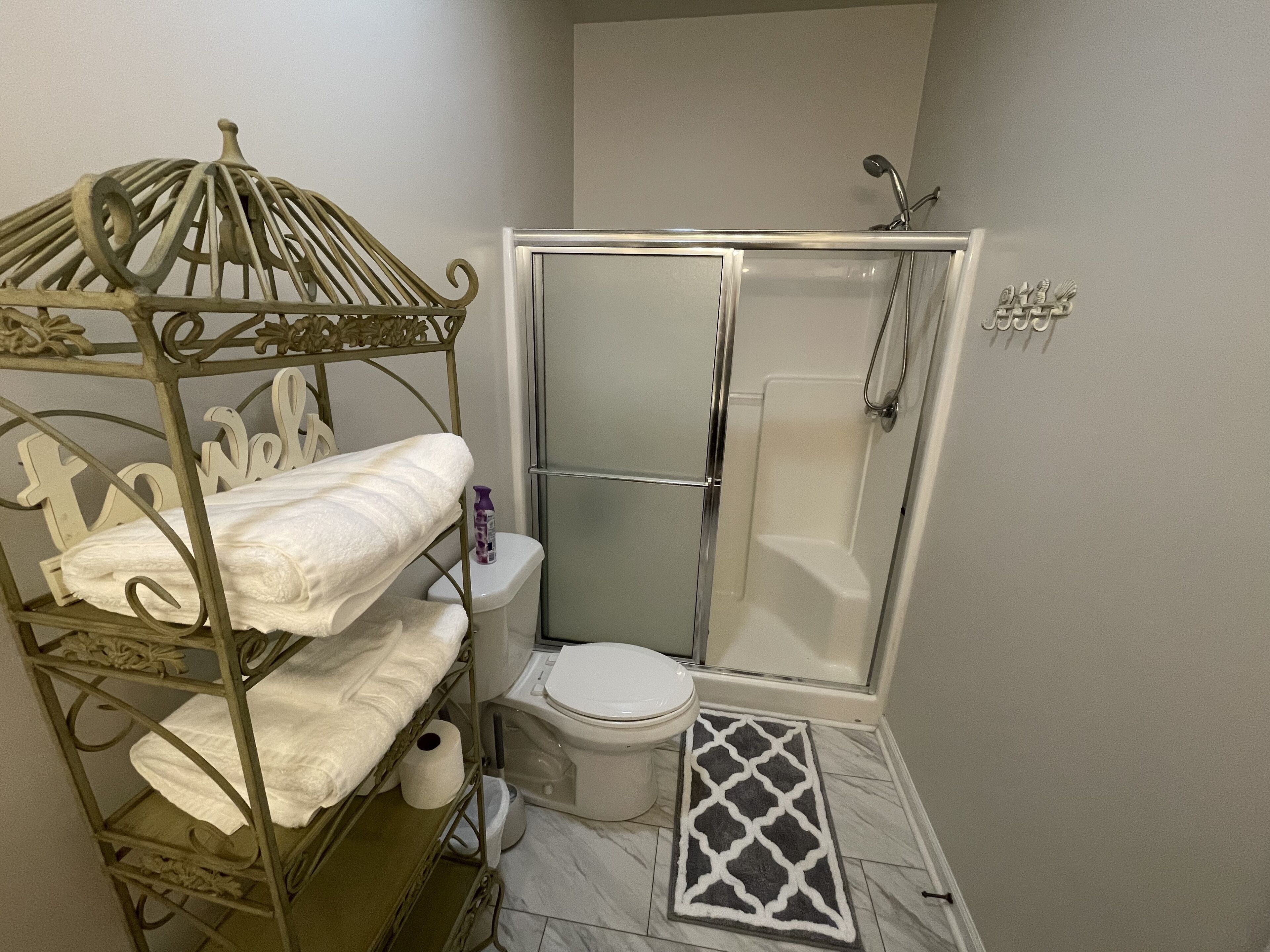 Une salle de bain avec douche, toilettes et un lit superposé en métal, ainsi que des serviettes.