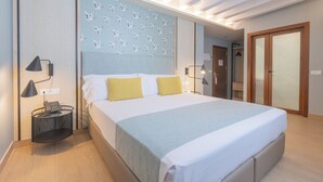A modern hotel room with a large bed, a bedside table with a lamp, a wall-mounted phone, and a patterned headboard. - Soho Boutique Columela (Cádiz)
