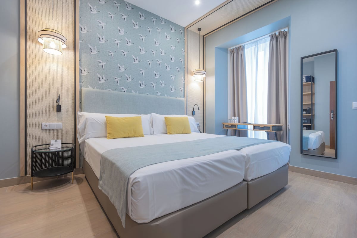 A hotel room with a large bed, two bedside lamps, a wall-mounted TV, and a mirror.