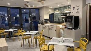 A modern dining area with yellow chairs and tables, a kitchen counter, and a ceiling fan. - Soho Boutique Columela (Cádiz)