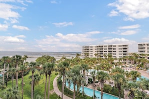 A resort with a pool, palm trees, and a view of the ocean.