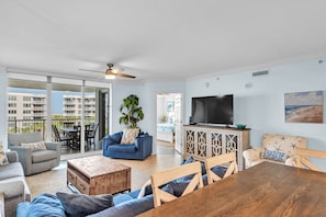 A living room with a TV, a wooden dining table, and a balcony with outdoor furniture.