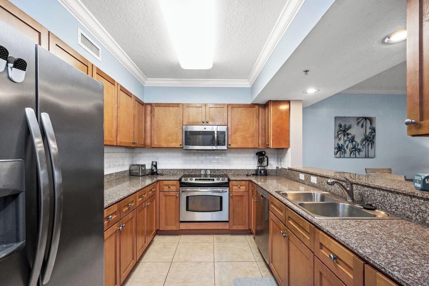 A modern kitchen with stainless steel appliances, wooden cabinets, granite countertops, and a large island with a sink.