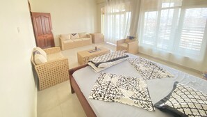 Een hotelkamer met een bed, twee slaapbanken, een salontafel en een raam met gordijnen.