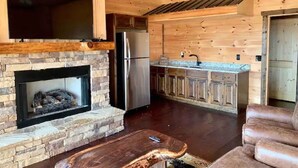 A cozy living room with a stone fireplace, wooden walls, a flat-screen TV, and a leather sofa. - Breathtaking LongRange Mntn Views 10min downtown BR & McCaysville Riverwalk (Blue ridge)