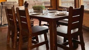 A dining area with a wooden table set for four, surrounded by wooden chairs, large windows offering a view of the landscape, and a wooden ceiling. - Breathtaking LongRange Mntn Views 10min downtown BR & McCaysville Riverwalk (Blue ridge)