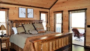 A wooden cabin bedroom with a large bed, two framed deer antlers on the wall, and a balcony with a chair. - Breathtaking LongRange Mntn Views 10min downtown BR & McCaysville Riverwalk (Blue ridge)