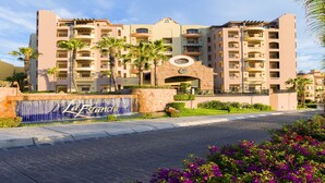 A multi-story hotel with a central courtyard, palm trees, and a tiled entrance.