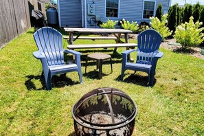 Un pati amb dues cadires Adirondack blaves, una taula de picnic de fusta i una xemeneia.