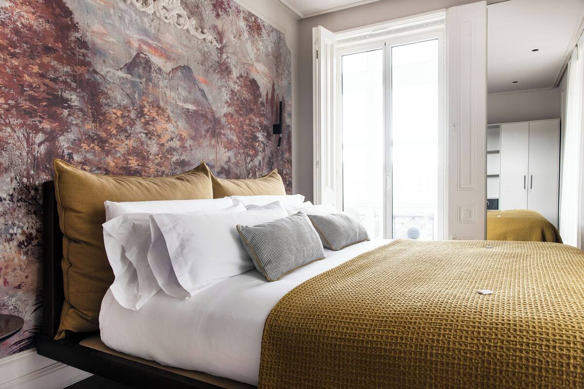 A bedroom with a large bed, a textured wall, and a view of the room.