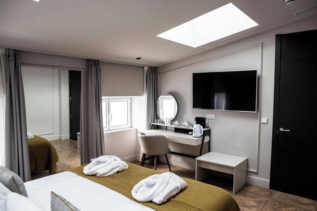 A hotel room with a bed, a desk, a chair, a TV, and a window.