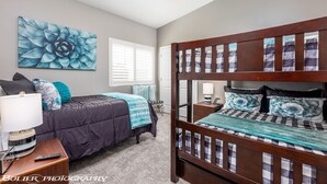 Um quarto com uma cama de solteiro, uma cama individual, um ventilador de teto, uma janela com persianas e uma grande obra de arte floral na parede.