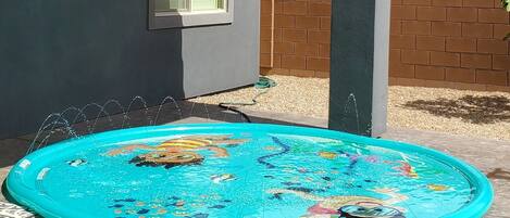 Ein Haus mit einem blauen aufblasbaren Pool im Garten.