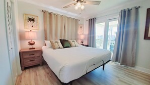 A bedroom with a bed, nightstands, a ceiling fan, and a view of the outside. - Salty Lime, Pet Friendly! Beach House!  Sleeps 8 Steps from the beach! (Gulf Shores)