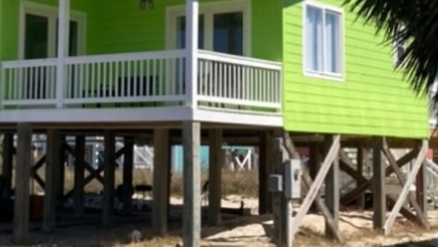 A two-story house with a balcony, a small window, and a deck. - Salty Lime, Pet Friendly! Beach House!  Sleeps 8 Steps from the beach! (Gulf Shores)