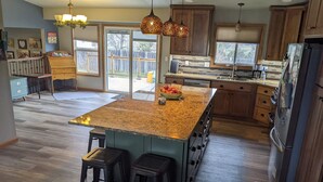 A spacious kitchen with a large island, wooden cabinets, and a view to the backyard. - Sturgis Rally rental; great location; next to I-90 and Harley Davidson (Rapid City)