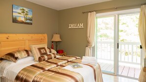 A bedroom with a bed, a painting, a 'DREAM' sign, and a view through a sliding door. - Cozy Family Cottage, Sleeps up to 10 Persons & Fully Equipped (Maynooth)