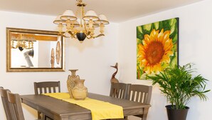 A dining room with a wooden table, chairs, a chandelier, a vase, and a sunflower painting. - Cozy Family Cottage, Sleeps up to 10 Persons & Fully Equipped (Maynooth)