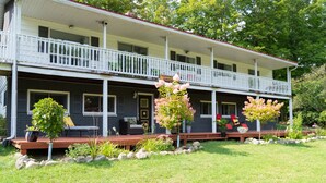 A two-story building with a porch, potted plants, and outdoor seating. - Cozy Family Cottage, Sleeps up to 10 Persons & Fully Equipped (Maynooth)