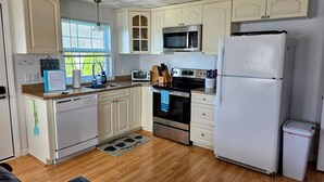 A kitchen with white cabinets, a stainless steel oven, a microwave, and a refrigerator. - 2 BR beach condo, 1 block from shore! (Narragansett)