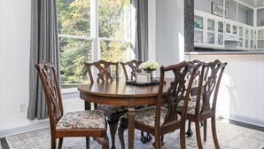Un coin repas avec une table ronde, six chaises et une fenêtre avec des rideaux.