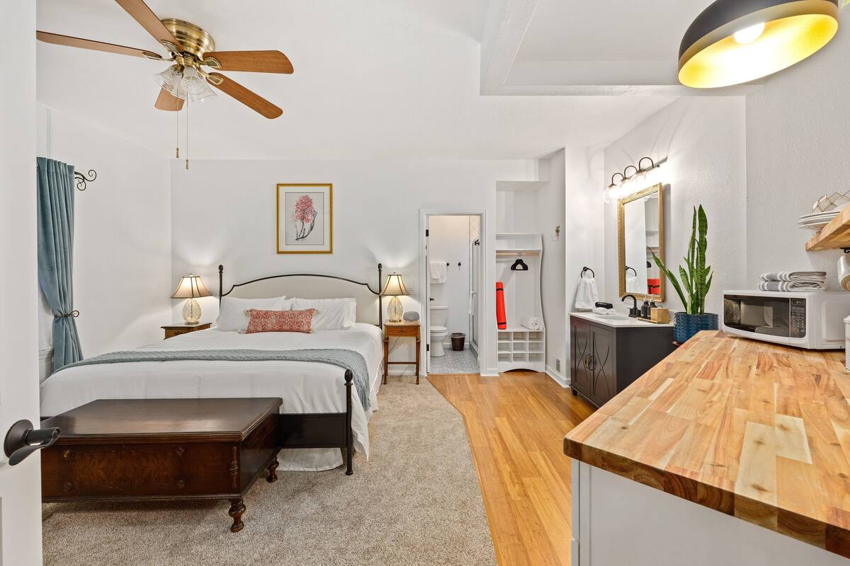 A bedroom with a bed, bedside tables, a ceiling fan, and a wooden bedside table.