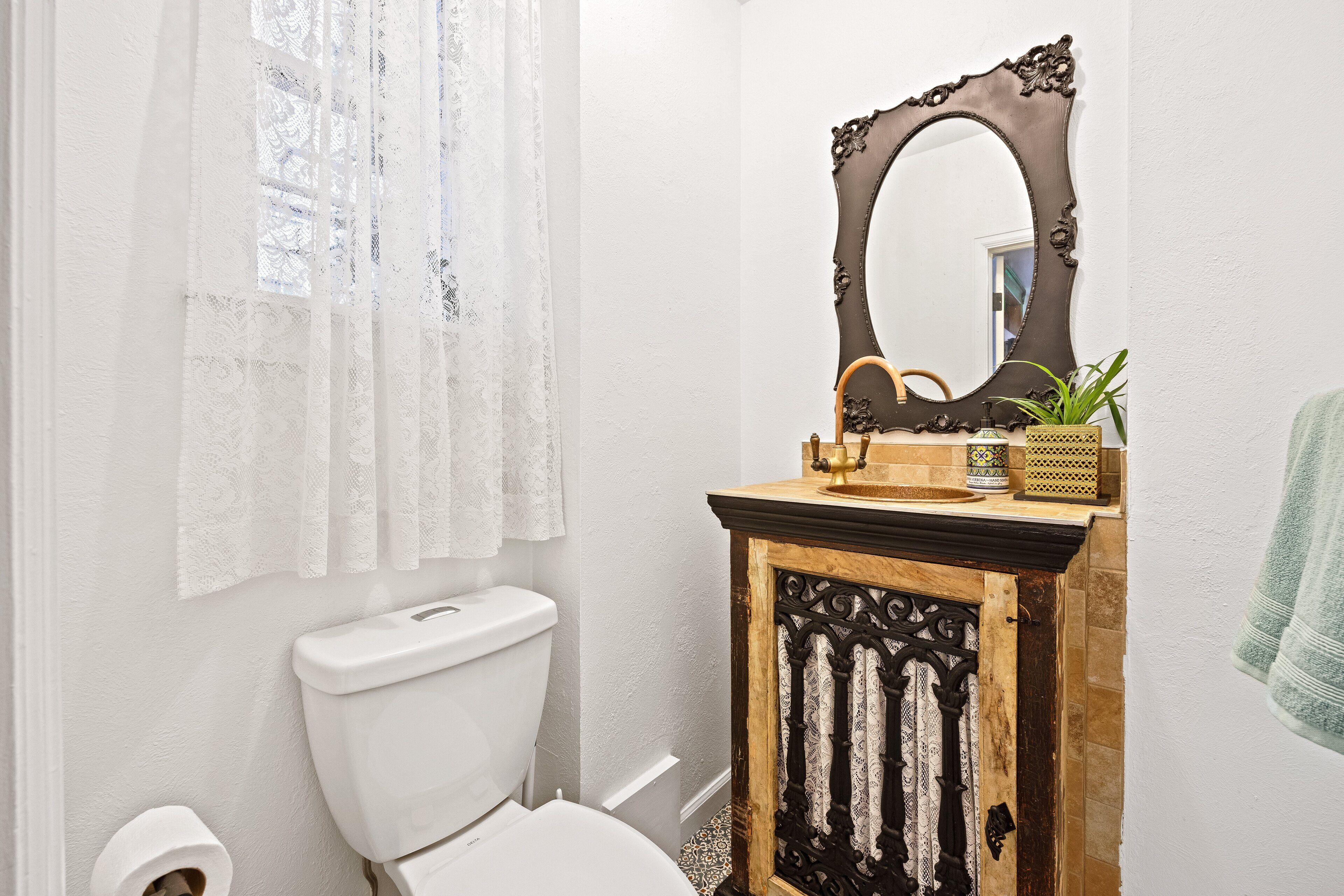 A bathroom with a toilet, a sink with a mirror, and a towel hanging on the wall.