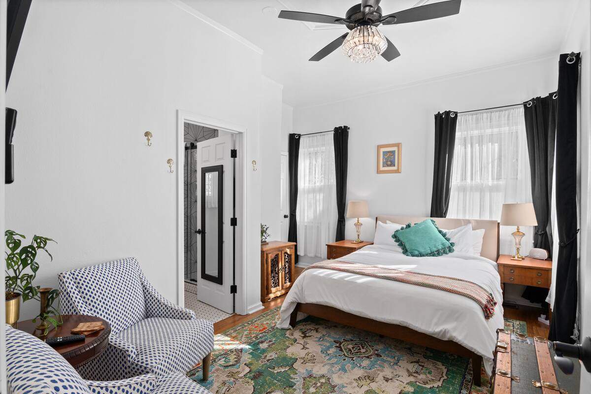 A bedroom with a bed, nightstands, a ceiling fan, and a patterned rug.