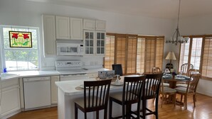 A modern kitchen with white cabinets, a built-in microwave, and a dining area with wooden chairs and a table set for four.