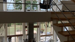 A spacious interior with a high ceiling, large windows, a staircase, and a dining area. - Fantastic view and magical sunsets! (Algutsrum)