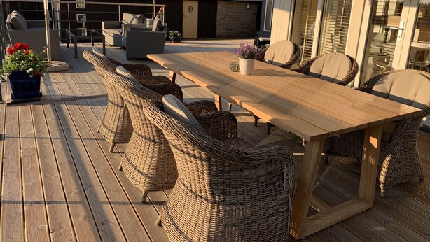 An outdoor patio with a long wooden table and wicker chairs, a potted plant, and a pergola overhead. - Fantastic view and magical sunsets! (Algutsrum)