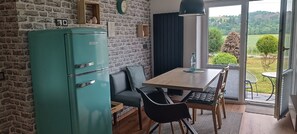 A kitchen with a teal refrigerator, a wooden dining table with black chairs, and a view of the outdoors through a glass door. - 2 Bedroom Condo in Niederwiesa (Niederwiesa)