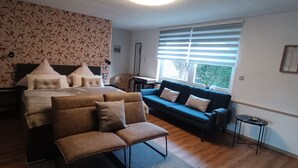 A bedroom with a large bed, a blue sofa, a small table, and a patterned wall. - 2 Bedroom Condo in Niederwiesa (Niederwiesa)
