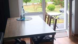 A dining area with a table and chairs, a bottle of water, and a view of a garden through a glass door. - 2 Bedroom Condo in Niederwiesa (Niederwiesa)