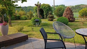 An outdoor patio with a round table and two chairs, surrounded by a grassy area with a view of a forested landscape. - 2 Bedroom Condo in Niederwiesa (Niederwiesa)
