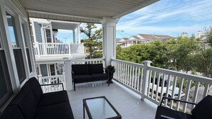 A covered porch with a seating area, a small table, and a view of neighboring houses. - 3 Bedroom House, 1 Block from Beach and Boardwalk (Ocean City)